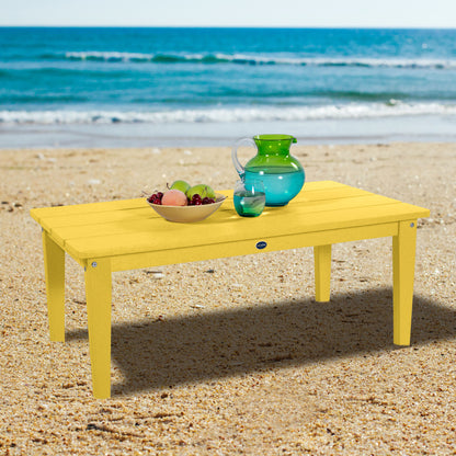 Yellow Sunrise Coast conversation table on beach with water pitcher and fruit
